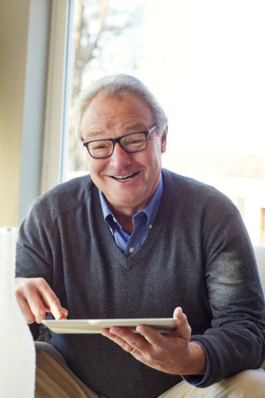 So much to do when you have wifi. a senior man using a tablet at home.の写真素材