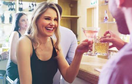 Im having so much fun getting to know you. a young man and woman toasting with their drinks in a nightclub.の写真素材