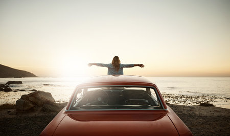 Welcome bliss with open arms. a young woman enjoying a road trip along the coast.の写真素材