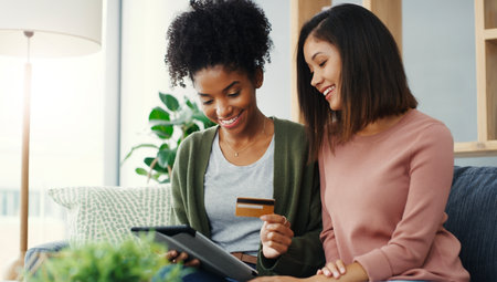 So weve agreed on this shirt. two attractive young women using a tablet together for online shopping while sitting on the sofa.の写真素材