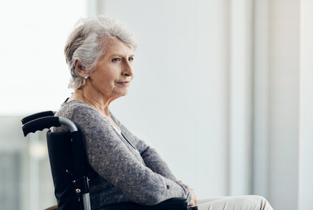 Aging gracefully. a senior woman looking thoughtful while sitting in her wheelchair.の写真素材