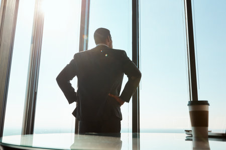 He does business on a whole new level. Rearview shot of a young businessman looking out the window in an office.の写真素材