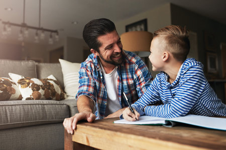 He stays involved in his kids life. a father helping his little son with his homework.の写真素材