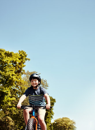 Kids learn through their own exploration. a young boy riding his bicycle through his neighbourhood.の写真素材