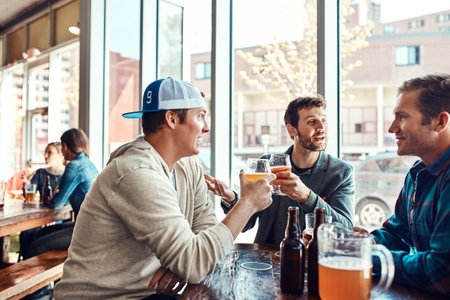 Nothing like a cold one with the mates. three male friends having drinks in a bar.の写真素材