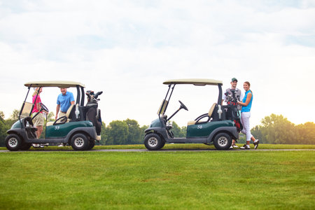 Family day on the golf course. two couples with golf carts spending a day on the golf course.の写真素材