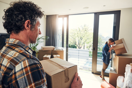 Where can it be. a focused middle aged couple packing out a boxes at their new home inside during the day.の写真素材