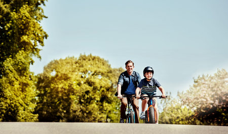 Out and about on their bikes. a young boy and his father riding together on their bicycles.の写真素材