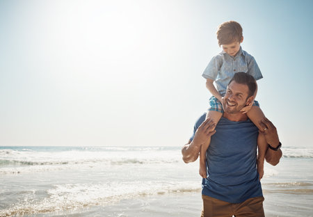 The days are brighter when theyre together. a father carrying his little son on his shoulders at the beach.の写真素材
