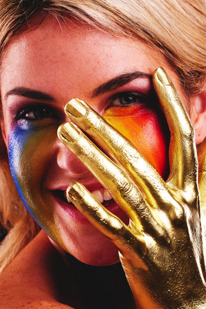 Gold hand, woman and beauty portrait with color paint cosmetics on skin and face in studio. Female model person with a happy smile for art deco, fantasy and creative makeup with metallic shineの写真素材