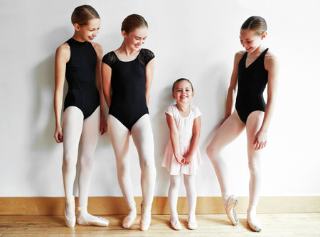 Every ballerina was once a beginner. a group of young ballerinas teaching a little girl ballet in a dance studio.の写真素材