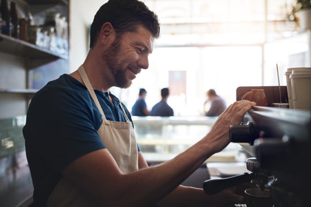 I promise this will be the best coffee youve had. a barista operating a coffee machine in a cafe.の写真素材