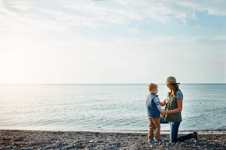 Shes always trying to be the best mom. a young woman and her son enjoying a walk by the water.