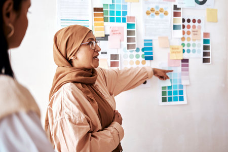 Strategy, collaboration and presentation with a business muslim woman talking to her team in the office. Creative, planning and teamwork with a female manager teaching or coaching an employee groupの写真素材
