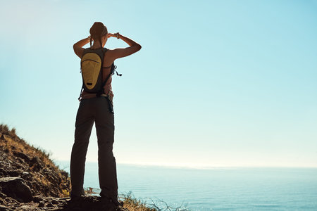 Surrounded by spectacular scenery. Rear view shot of a young woman admiring the view from the top of...