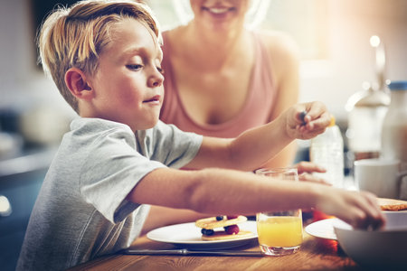 He has such a healthy appetite. a little boy having breakfast at home.の写真素材