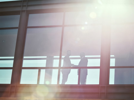 Corporate collaborations. Low angle shot of two businessman shaking hands in an office corridor.の写真素材
