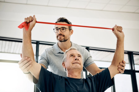 Ensuring a full range of movement. a friendly physiotherapist helping his mature patient to stretch...