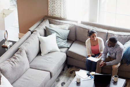 Keeping home affairs in order. a young couple going through paperwork together on the sofa at home.の写真素材