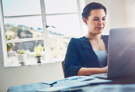 Her own productive corner. a young businesswoman using a laptop at her work desk.の写真素材