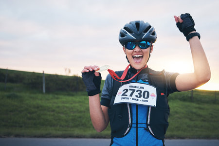 Celebrate, sport and portrait of happy woman with medal for winning outdoor cycling race or triathlon. Happiness, win and cyclist with smile, fitness and excited celebration for gold winner at sunsetの写真素材