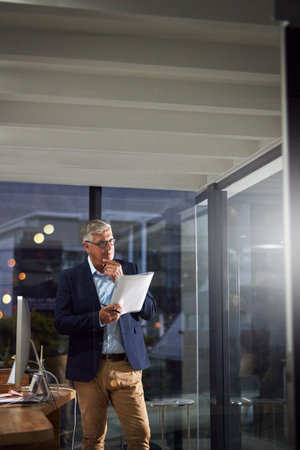 Putting in the hours. a dedicated businessman working alone in his office after hours.の写真素材