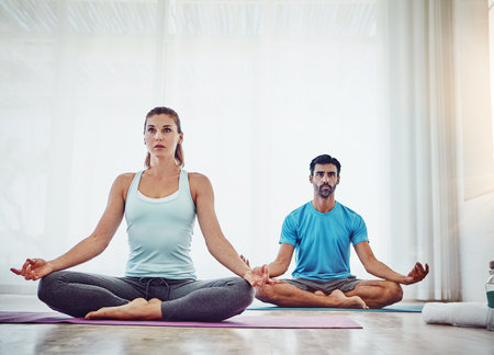 Inhale love, exhale peace. a couple practising yoga at home.の写真素材