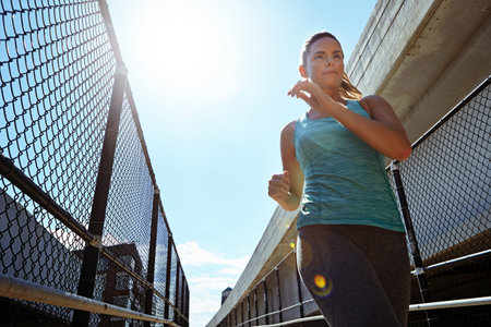 I exercise so I can live longer. a sporty young woman running on a footbridge.