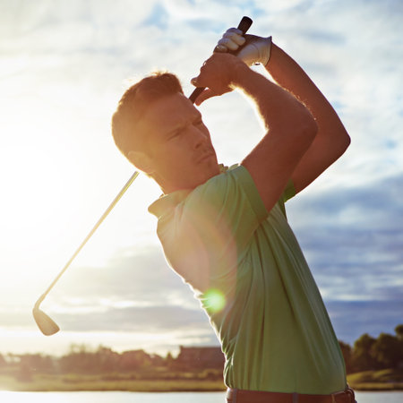 Hes got the secret to a solid swing. a man practicing his swing on the golf course.の写真素材