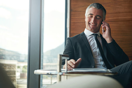 Another day, another telephonic business deal. a businessman answering a phonecall while sitting in his office.の写真素材