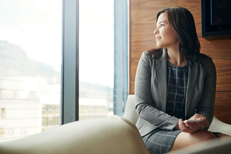 Should I make that call. a happy young businesswoman sitting in an office chair.の写真素材