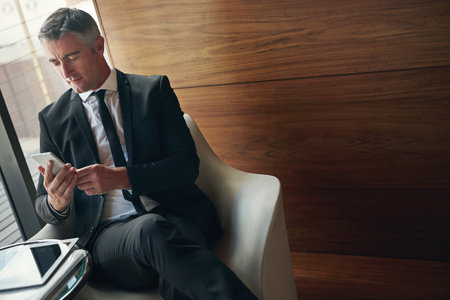 Smartphones make business a breeze. a mature businessman using his phone at work.の写真素材