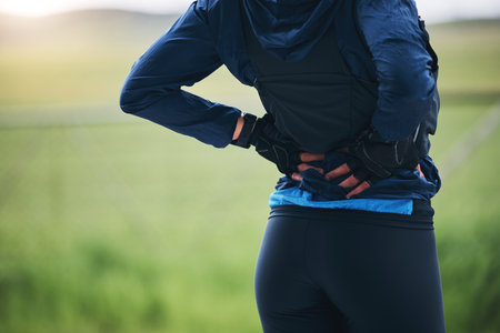 Back pain, fitness and sports woman outdoor with scoliosis, health risk and burnout from marathon. Closeup female athlete, spine injury and joint problem of tired muscle, first aid and emergency careの写真素材