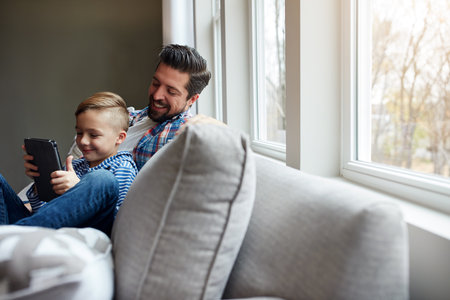 Theyve got entertainment to last them all day long. a little boy using a digital tablet with his father at home.の写真素材