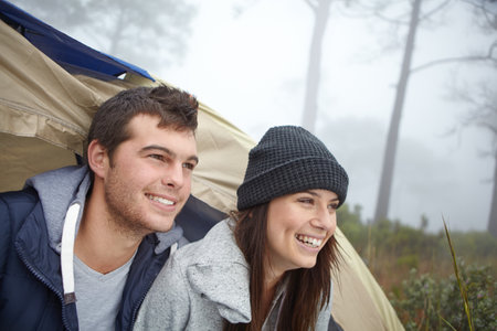 The camping trip theyll remember forever. a young couple sitting inside their tent while on a camping trip.の写真素材