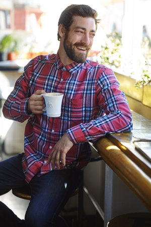 Without coffee, a beautiful day would be nothing. a young man holding a cup of coffee in a cafe.の写真素材