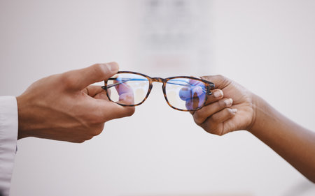 Glasses, optometry and hands of an optometrist and person for decision, buying and help with vision. Consulting, helping and an optician giving eyewear frames and prescription lenses to a customerの写真素材