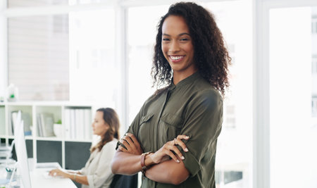 To be successful youve got to know your worth. Portrait of a confident young businesswoman working in a modern office with her colleague in the background.の写真素材