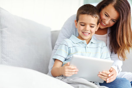 I need moms help. A mother helping her son use a digital tablet.の写真素材