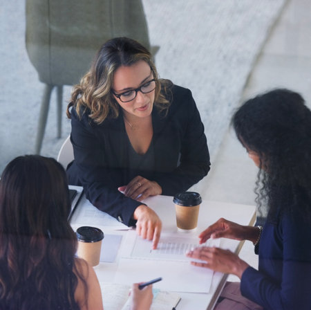 Heres what we wanna focus on...High angle shot of three young businesswoman sitting in the boardroom during a management meeting.の写真素材