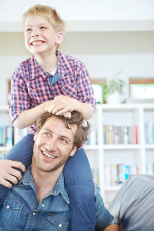 Hanging out with dad on the weekend. a young boy sitting on his fathers shoulders.の写真素材