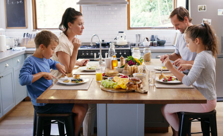 And this is what love looks like. two affectionate young parents having breakfast with their kids in the kitchen at home.の写真素材