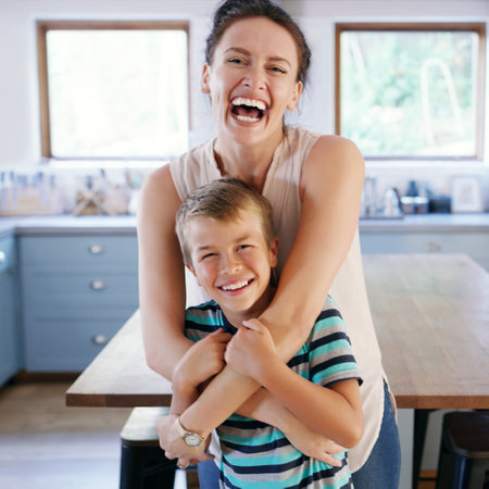 Shes a happy momma. Cropped portrait of an affectionate young mother looking ecstatic while holding her son in their kitchen at home.の写真素材