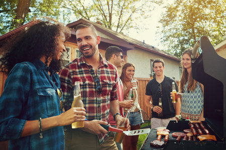 Love is when he does the cooking...a group of friends having a barbecue outside.の写真素材