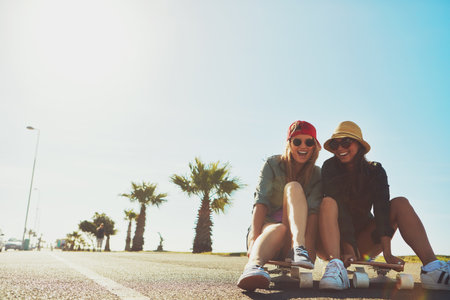 Promenade chilling. two friends hanging out on the boardwalk with a skateboard.の写真素材