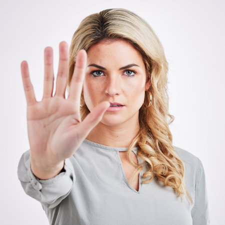 Stop hand, woman and portrait in a studio with protest, emoji and warning hands gesture. Serious, self defense and female model with reject, refuse and no palm sign isolated with white backgroundの写真素材