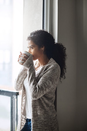 I needed this time to myself. an attractive young woman relaxing at home with a cup of coffee.