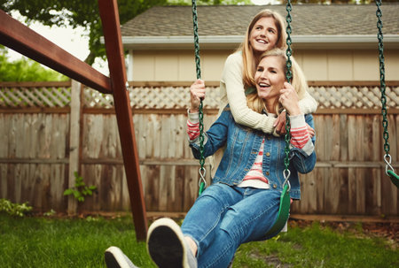 Showing her daughter unconditional love. a mother and her daughter playing on a swing in their backyard.の写真素材
