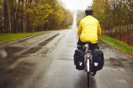 His fitness comes first. Rearview shot of a male cyclist enjoying a bike ride on a wet winters morning.の写真素材