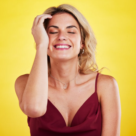 Laughing, eyes closed and face of fashion woman, model or girl with elegance, style and chic clothes. Smile, funny and comedy joke for happy person in luxury apparel and isolated on yellow backgroundの写真素材